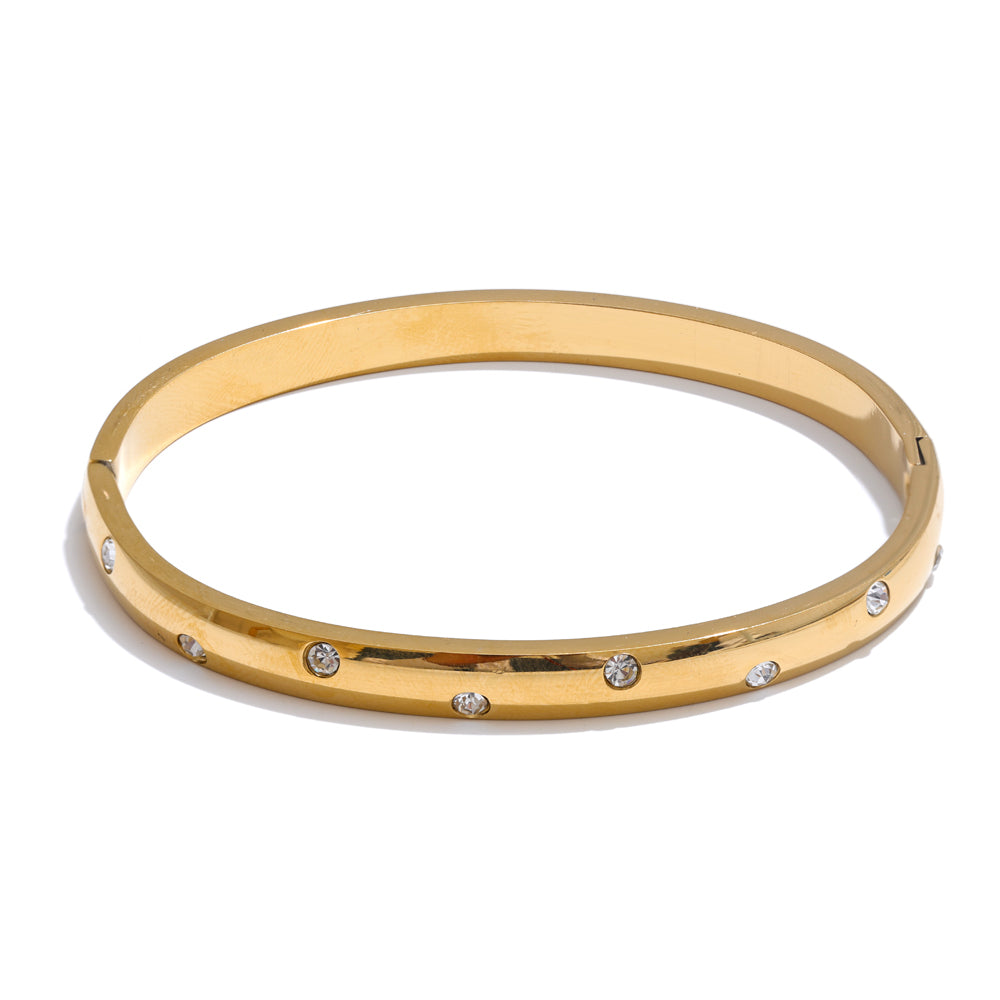 Gold bangle with embedded stones on a white background