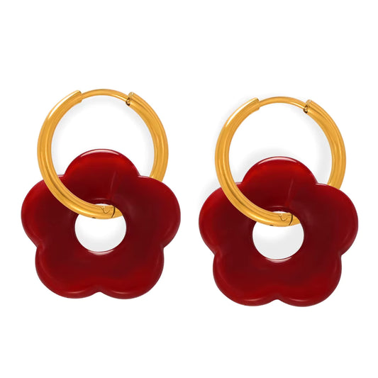 Gold hoop earrings with red flower-shaped connectors on a white background