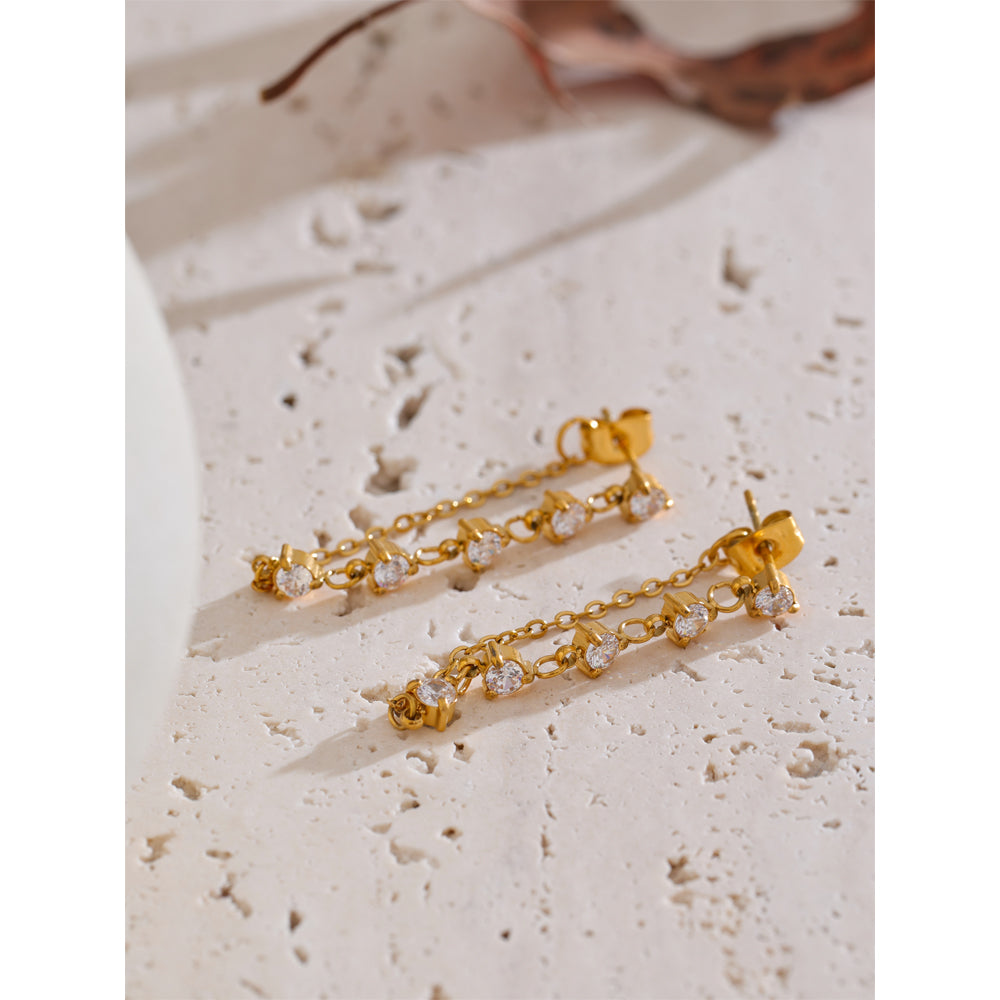 Gold earrings with small diamonds on a textured beige surface