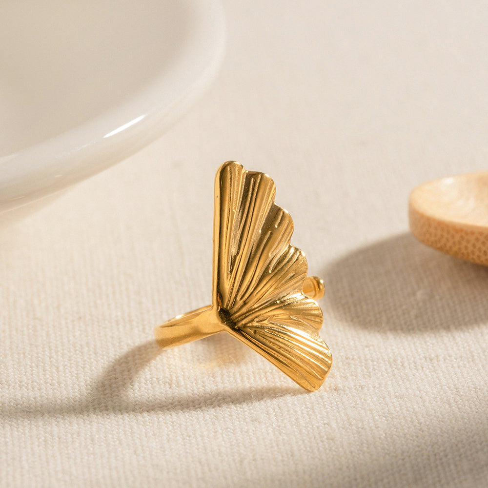 18k Gold plated leaf-shaped ring on a beige fabric background