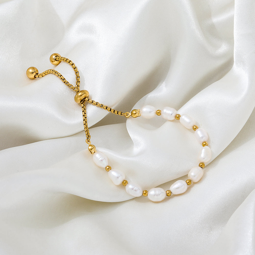 Pearl bracelet with gold accents on a white fabric background
