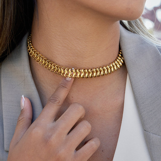 Gold chain necklace worn by a person with a blurred background