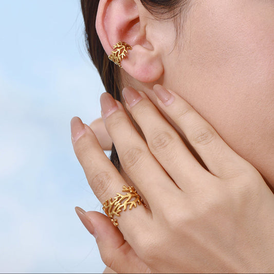 Woman wearing gold earrings and ring against a light blue background