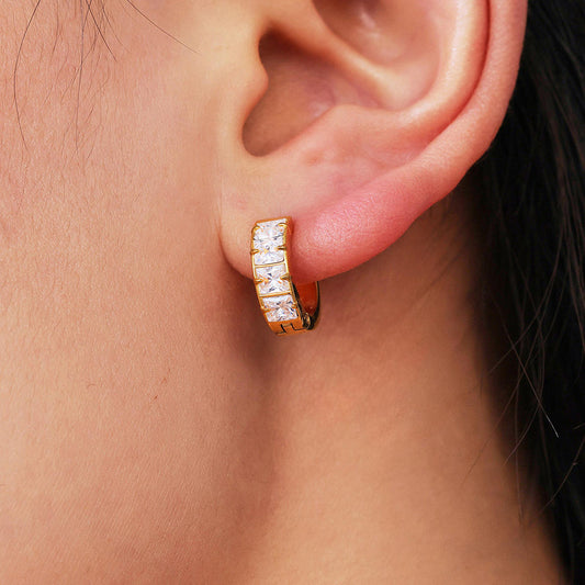 Gold hoop earring with diamonds worn by a person
