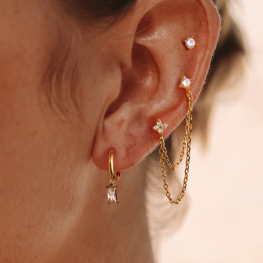 Close-up of an ear wearing gold earrings with zircons.