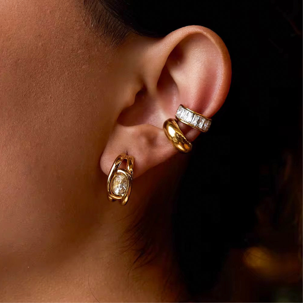 Close-up of an ear wearing a gold plated earring and two ear cuffs