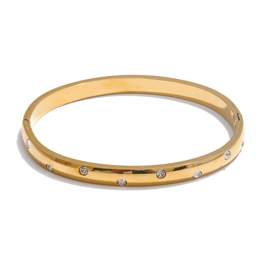Gold bangle with embedded stones on a white background