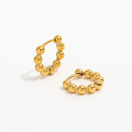 Gold hoop earrings with bead detailing on a white background