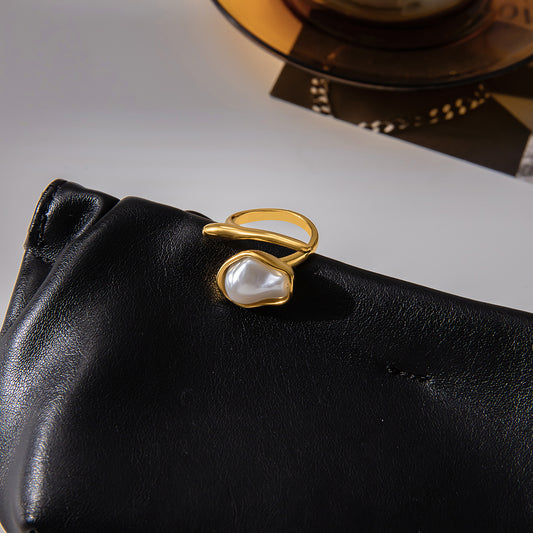 Gold ring with a pearl on a black leather surface