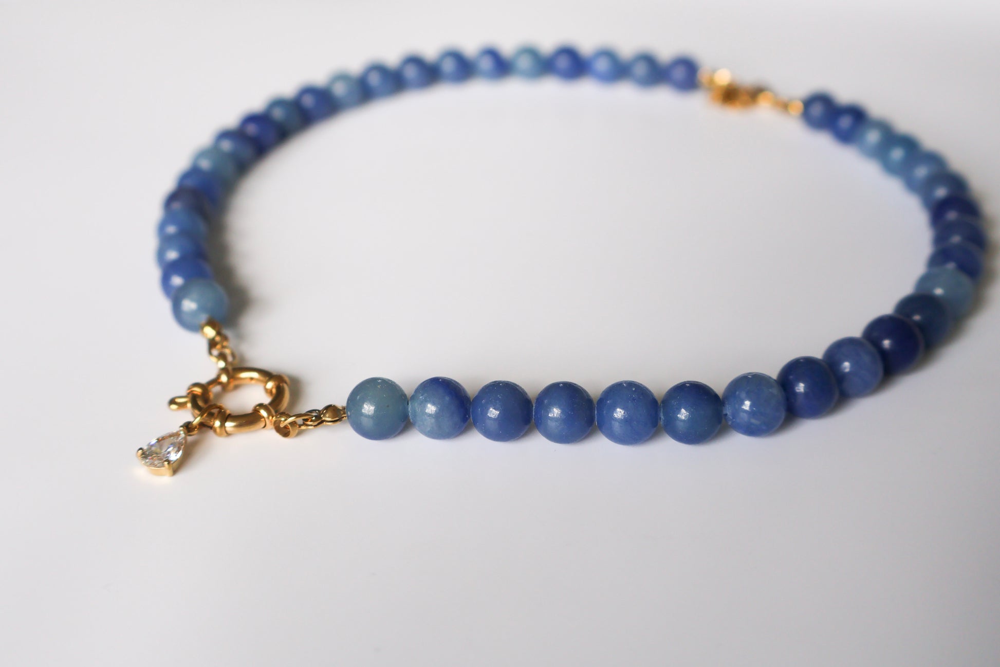 Blue beaded bracelet with a gold clasp on a white background