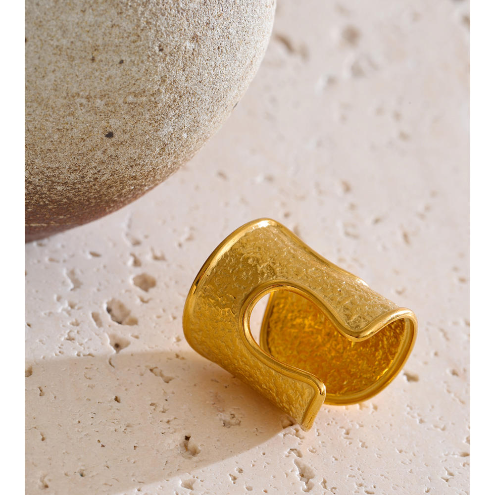 Gold ring with a textured design on a beige surface