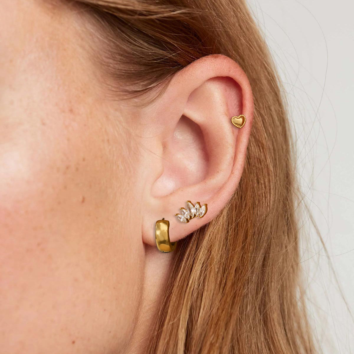 Close-up of an ear wearing gold hoop earrings with a blurred background