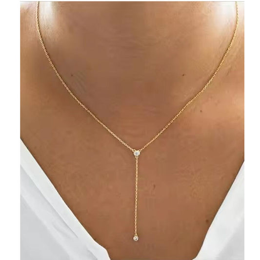 Gold necklace with a pendant on a person wearing a white top.