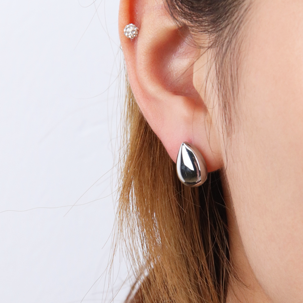 Silver drop stud earring on ear