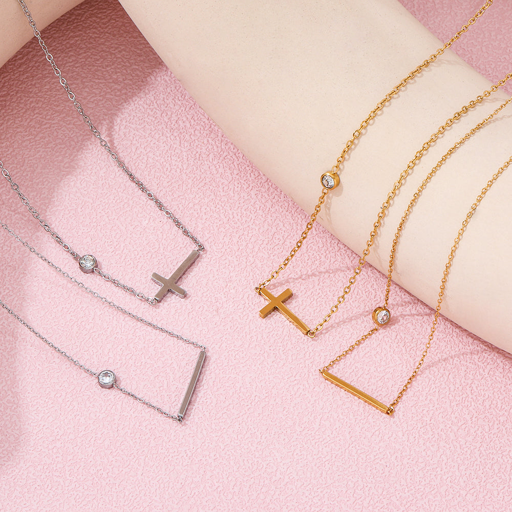 Gold and silver necklaces with pendants on a pink surface