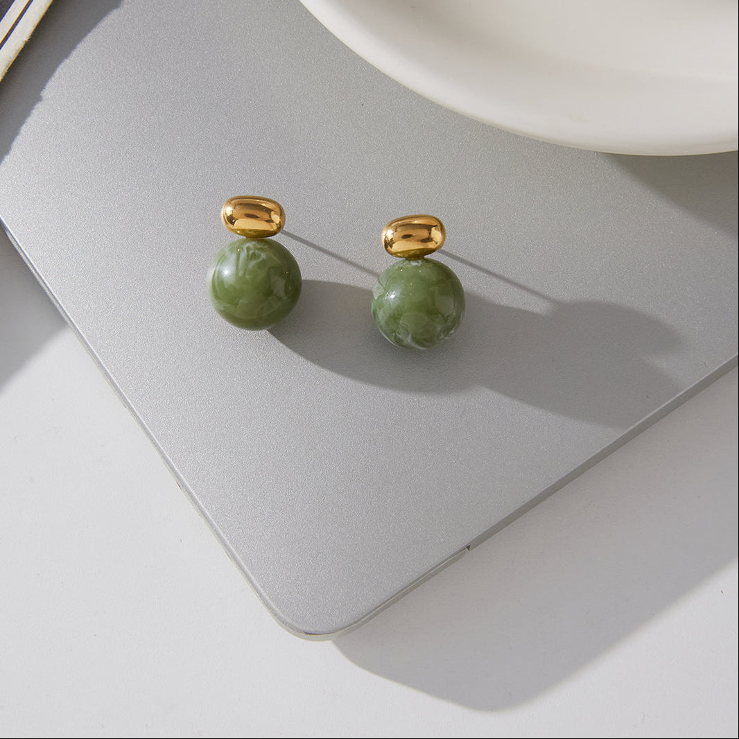 Green bead earrings with gold tops on a gray surface