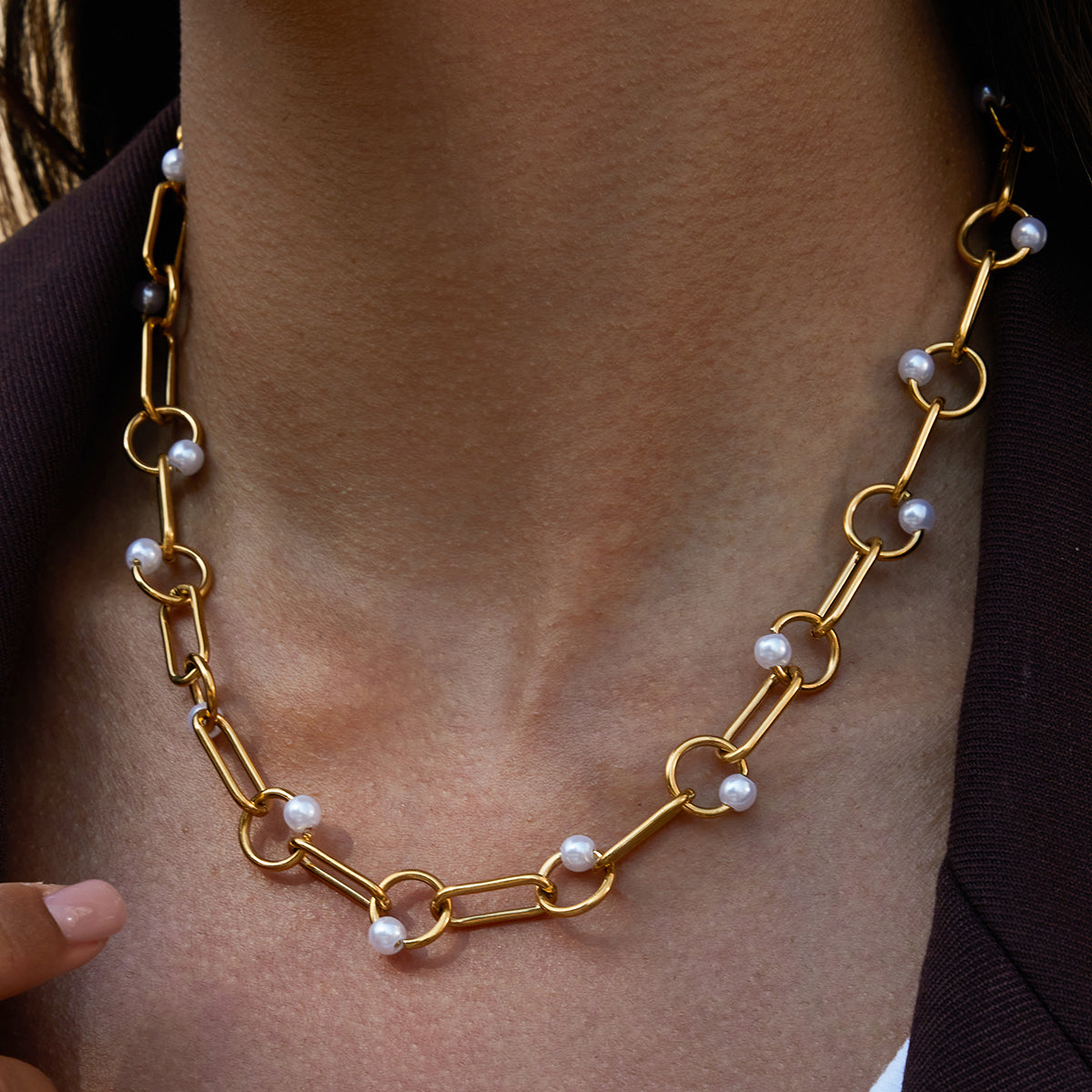 Gold chain necklace with pearls worn by a person