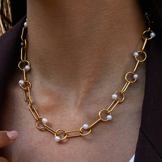 Gold chain necklace with pearls worn by a person