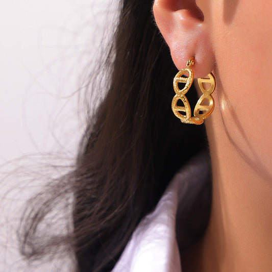 Gold earrings worn by a person with a neutral background