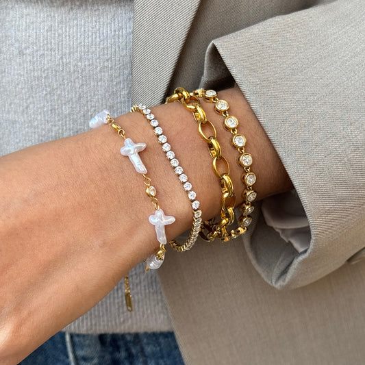 Close-up of a wrist wearing multiple gold bracelets with a neutral background