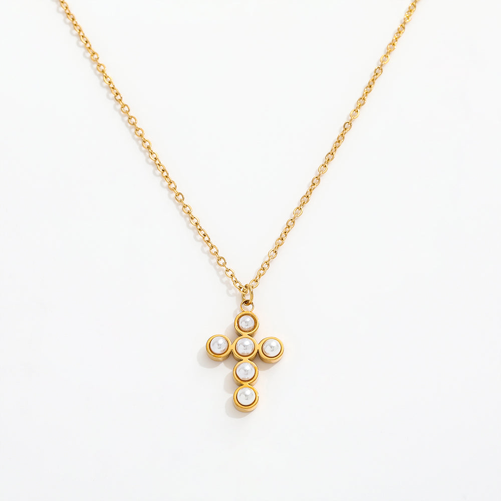 Gold necklace with a cross pendant featuring pearls on a white background