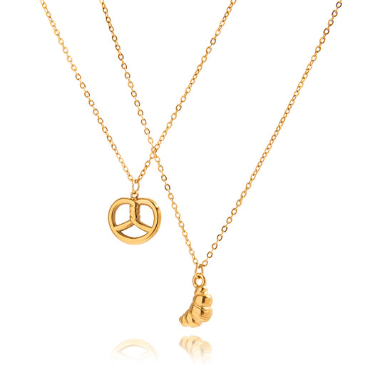 Two gold necklaces with pretzel pendant and croissant pendant on a white background