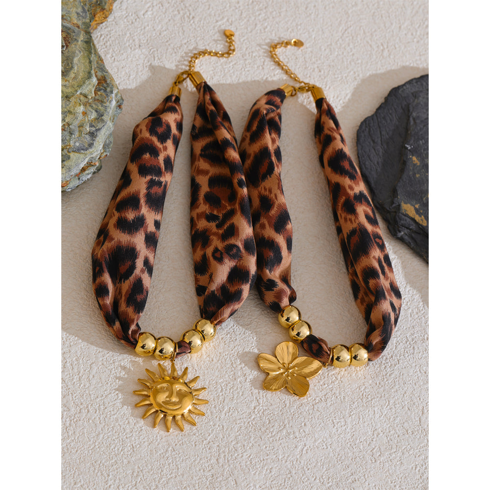 Leopard print scarf necklace with gold accents on a textured surface