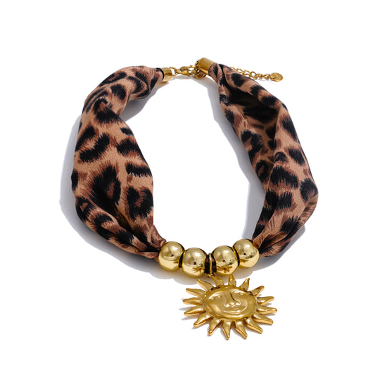 Leopard print necklace with gold beads and sun charm on a white background