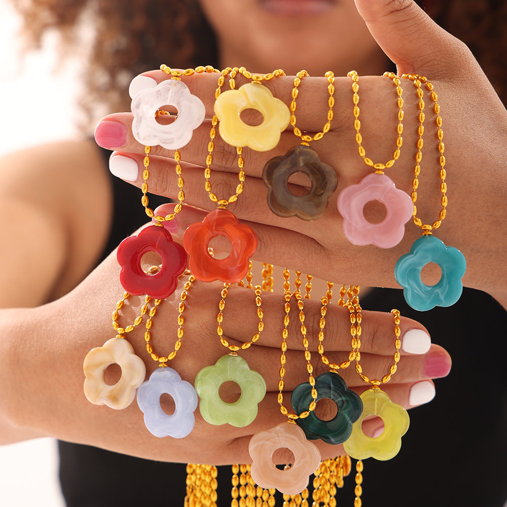 Colorful flower-shaped necklaces on a hand against a blurred background