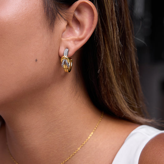 Close-up of a person wearing gold hoop earrings with a blurred background