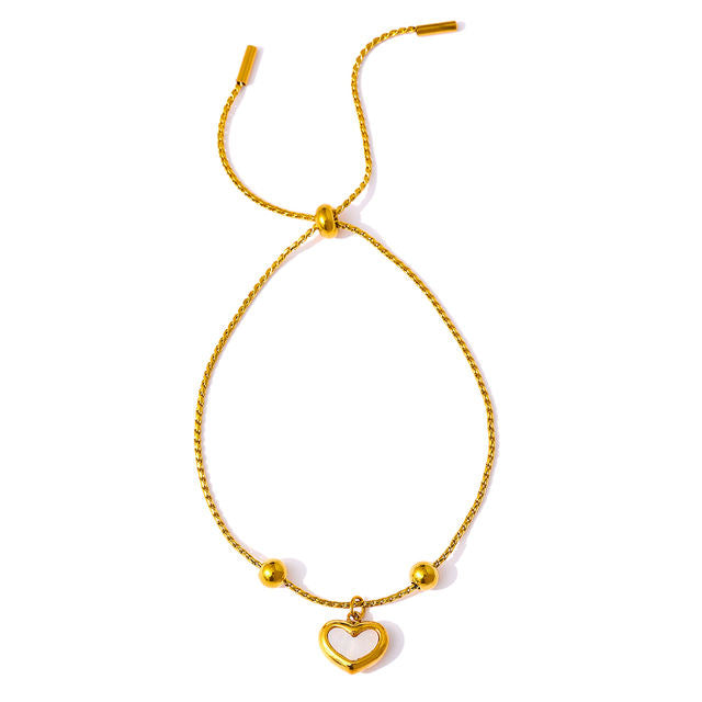 Gold bracelet with a heart-shaped charm on a white background