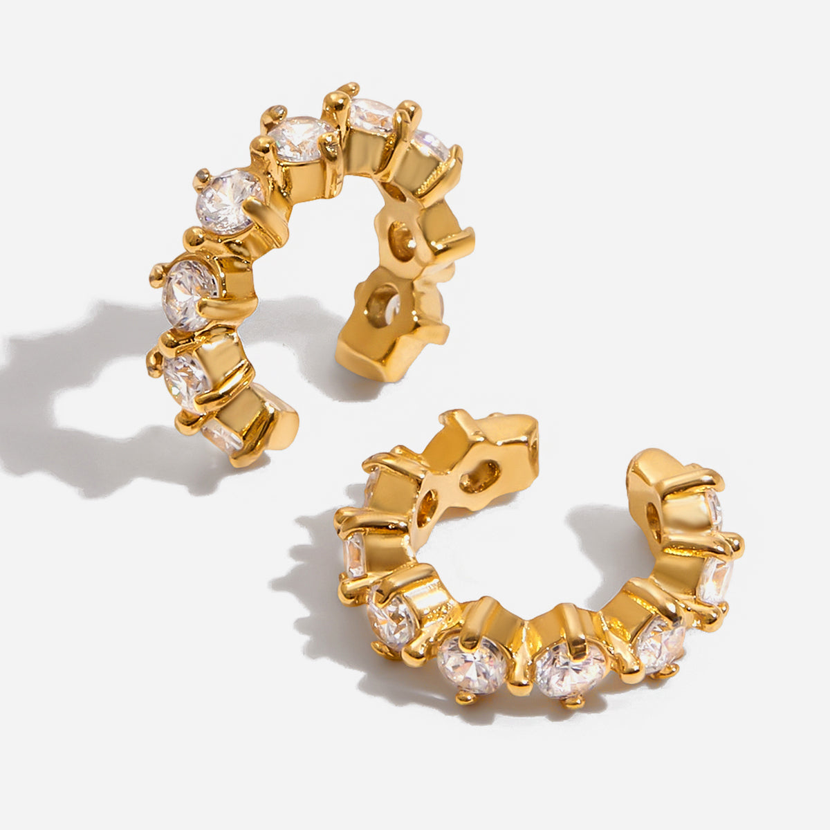 Gold hoop earrings with clear gemstones on a light gray background