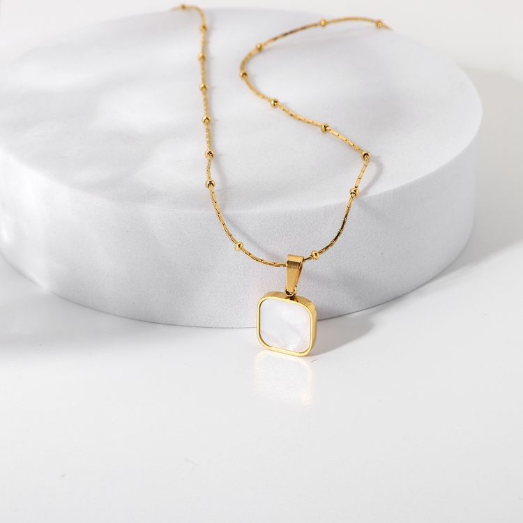 Gold necklace with a square pendant on a white background