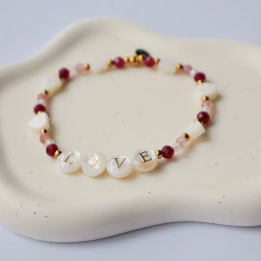 Bracelet with letter beads spelling 'LOVE' on a white cloud-shaped dish
