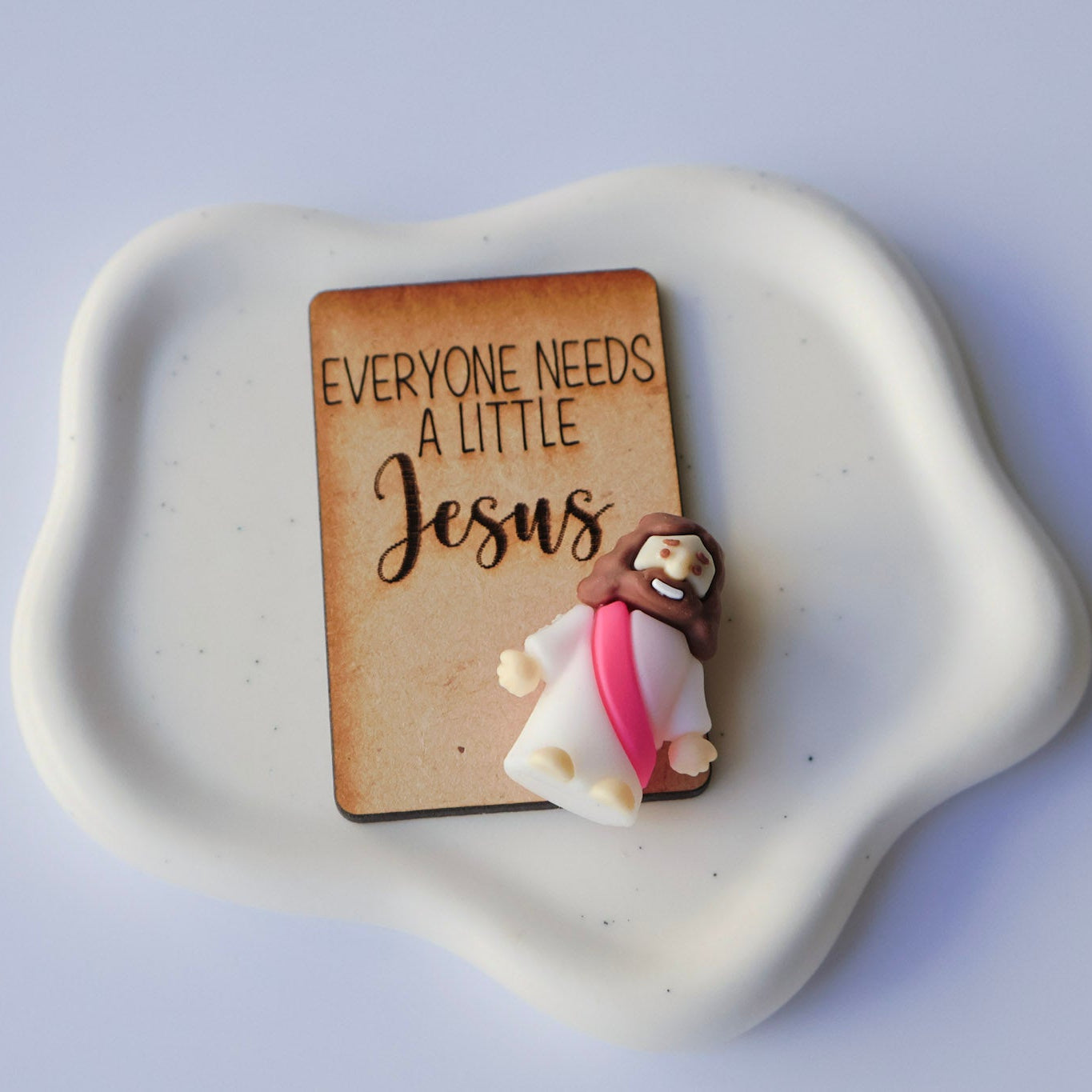 Mini Jesus Figurine with a wooden card that says Everyone needs a little Jesus on a white background