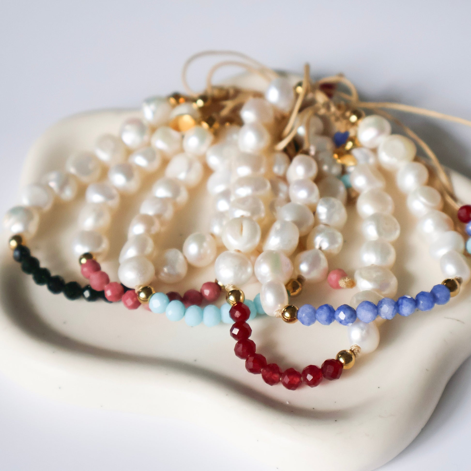 Set of pearl and gemstone necklaces on a white surface