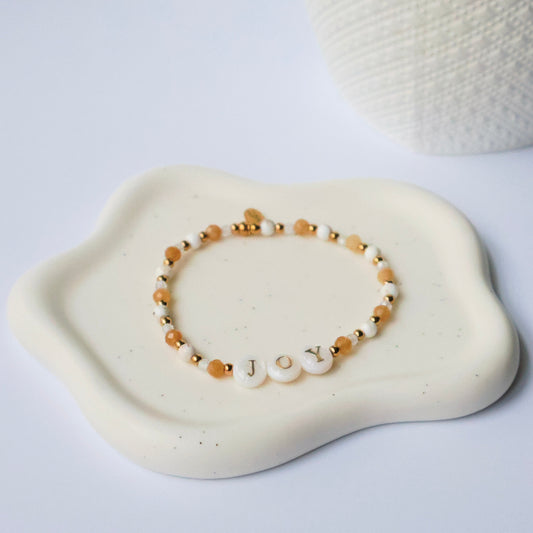 Bracelet with the word Joy and beads on a white surface